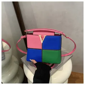 Macro detail of tricolor patchwork leather bag with golden V-shaped metal buckle