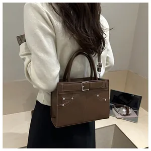 Brown square crossbody bag with rivet details shown in a modern office lifestyle setting