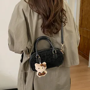 Detail view of black leopard print crossbody bag with plush kitten pendant accessory