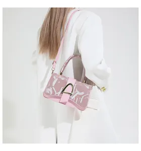 Vue détaillée d'un sac bandoulière rose avec boucle en métal sur un blazer blanc minimaliste