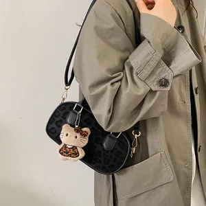 Close-up of leopard print handbag with a plush character charm and gold hardware