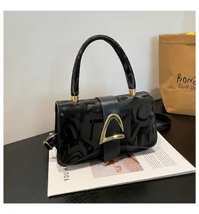 Détail du sac à main noir avec fermoir doré géométrique et motif embossé élégant