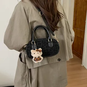 Detail of leopard print handbag with plush doll charm worn over a classic khaki trench coat