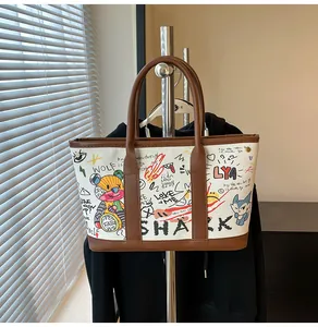 Λεπτομέρεια τσάντας tote γκράφιτι με χρωματιστά μπαλώματα, καφέ δερμάτινα λουράκια και καμβά