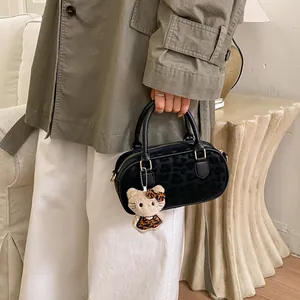 Detail of black leopard print Boston bag with plush mascot charm on white sofa