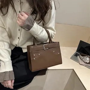 Brown leather square handbag for women with metallic studs and top handles in office setting