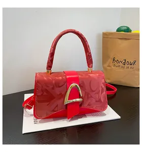 Détail de mini sac carré rouge avec fermoir doré en D et motif sur cuir texturé