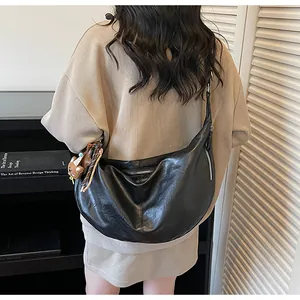 Close-up of black crescent bag in textured PU leather with cute bear charm and silver zipper