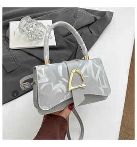Détail du sac gris argenté avec texture de lettres et fermoir en métal doré chic