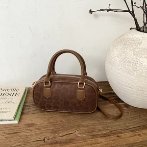 Detailed close-up of brown leopard print boston bag with gold metal buckles and matte texture