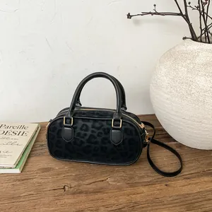 Detail of black leopard print Boston bag with gold metal hardware and suede texture
