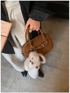 Close-up of a dark brown pebble leather handbag with metal buckle and plush bunny charm