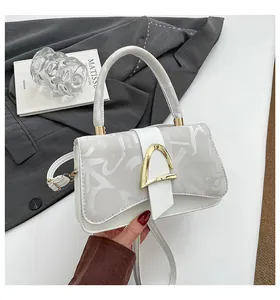 Détail de sac à main beige imprimé avec ferrures dorées et bandoulière élégante