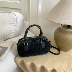 Detail of leopard print handbag with black faux fur texture and gold hardware on a wooden table