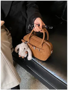 Detail of caramel brown handbag with plush bunny charm and silver buckle accents