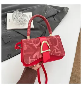 Détail du sac rouge avec boucle en D en métal doré et motifs de lettres texturés en relief