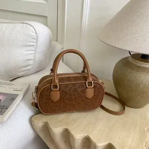 Detail of leopard print Boston bag with golden hardware and brown leather trim