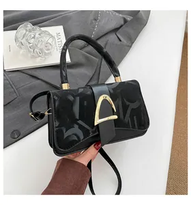 Détail du sac à main noir avec fermoir doré métallique et motif monogramme texturé