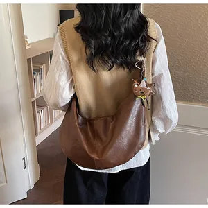 Close-up of brown faux leather half-moon bag with cute bear charm for daily wear