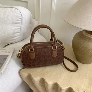 Detail of a brown leopard print boston bag with gold hardware and top handles