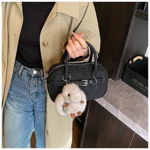 Close-up of a black matte leather handbag featuring a plush white bunny charm detail