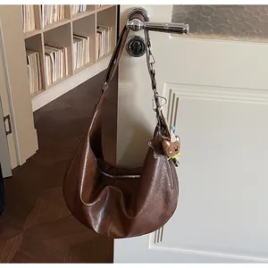 Close-up of brown vintage crescent bag with cute plush bear and star charms on a door