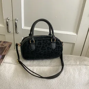 Close-up of black leopard print handbag with gold hardware on a white sofa