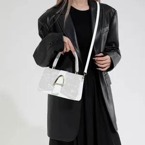 Petit sac carré en cuir blanc avec boucle dorée en D présenté sur un mannequin
