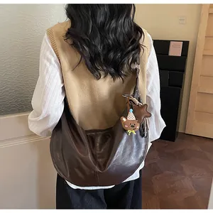 Detail showing deep brown hobo bag with cute bear charm and star pendant accessory