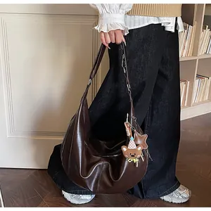 Deep brown crescent moon shoulder bag with glossy leather texture and cute bear pendant
