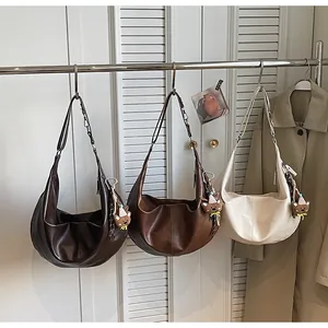 Three crescent shoulder bags in brown and beige with cute bear charms on a rack