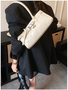 Creamy rectangular shoulder bag with strap detail on a model in a black blazer coat