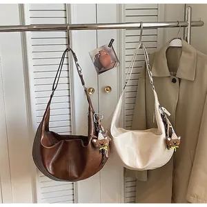 Detailed view of crescent hobo bags in brown and cream with cute teddy bear charms