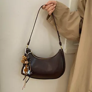 Détail du sac hobo marron foncé avec pendentif cœur léopard et accessoire à pompon
