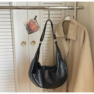 Detail of a black crescent hobo bag with adjustable strap hanging on a coat rack