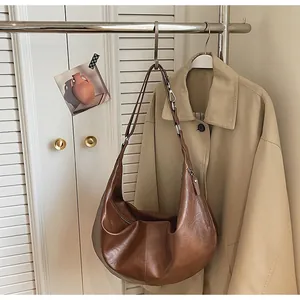 Detail view of a vintage brown crescent bag hanging next to a khaki trench coat