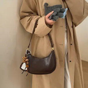 Détail du sac croissant marron foncé avec nœud léopard et breloque cœur élégante