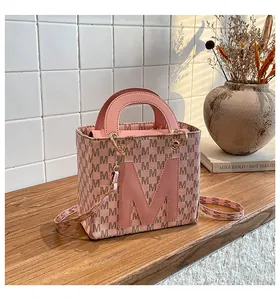 Detailed view of pink tote bag with brown M patterns and premium gold hardware accents