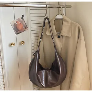 Detail view of smooth dark brown leather texture and stitching on crescent hobo bag