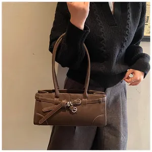 Detail of dark brown matte handbag with belt decoration and silver metal buckle