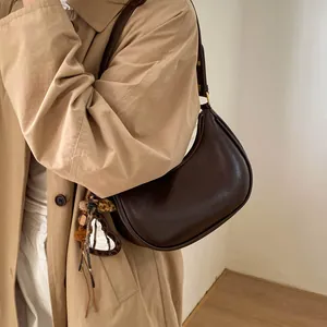 Détail du sac demi-lune en cuir marron foncé avec miroir cœur et breloque léopard