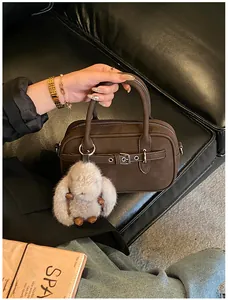 Detailed macro view of dark brown frosted handbag with buckle and plush rabbit charm