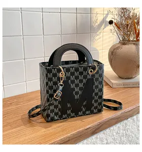 Close-up of black and grey patterned square tote bag with metallic hardware details