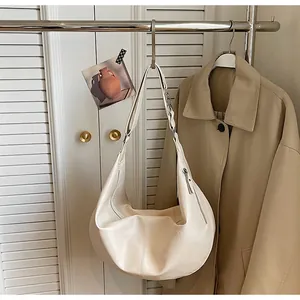 Close-up of minimalist cream crescent hobo bag with silver zipper on display