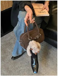 Detail of dark brown leather handbag with silver buckle and white plush bunny charm