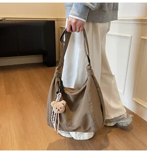 Detail of khaki canvas crossbody bag with Middie embroidery and plush bear charm
