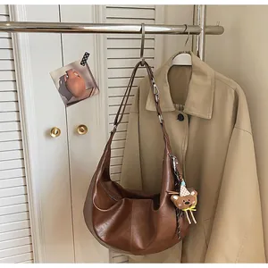Detail of brown crescent bag with matte leather texture and cute plush bear charm