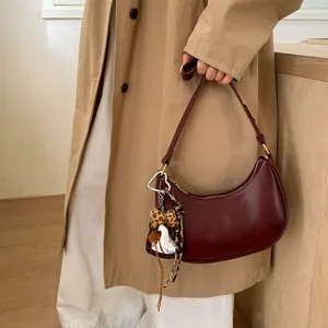 Détail du sac demi-lune bordeaux avec breloque léopard et pendentif cœur en argent