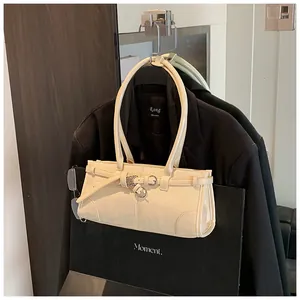 Close-up of cream shoulder bag with belt buckle detail against a black blazer backdrop