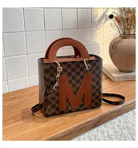 Side view of retro brown crossbody tote bag with M-letter pattern on wooden tabletop